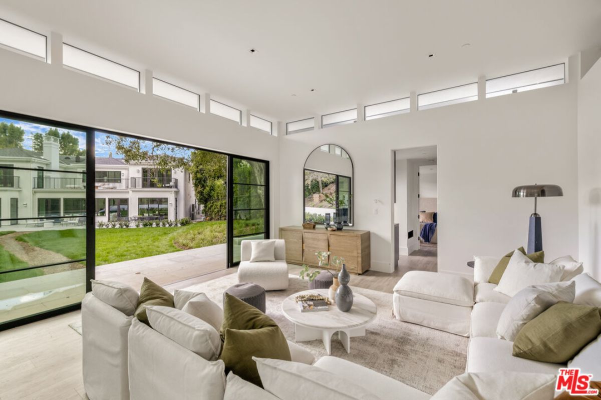 A living room with windows, white couches, a houseplant, and a center table.