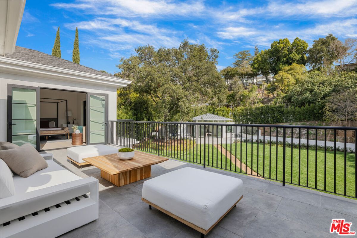 A terrace with a couch, ottoman, center table, and metal handrail.