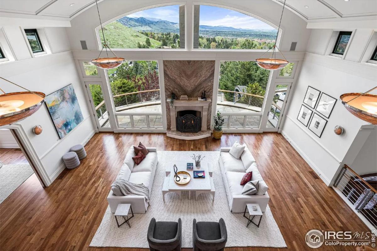 Living room with hardwood floors, glass walls and a fireplace.