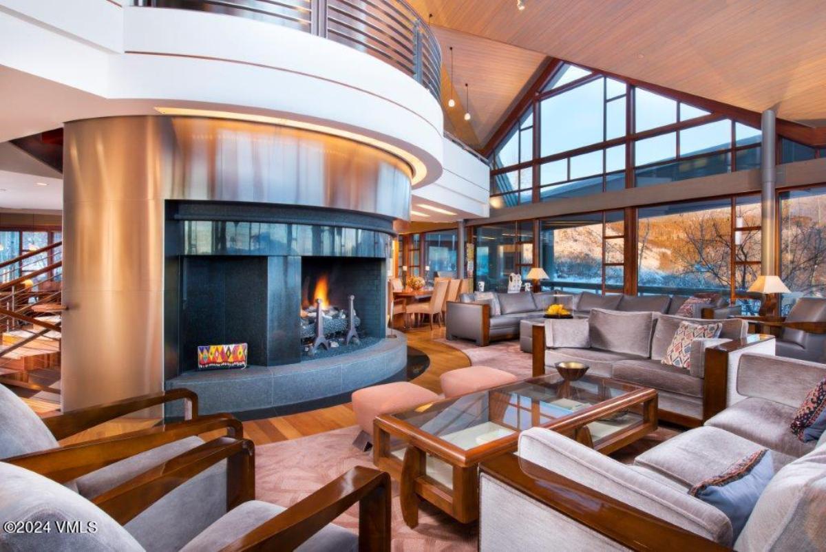 Living room with couches, a fireplace and floor-to-ceiling glass windows.