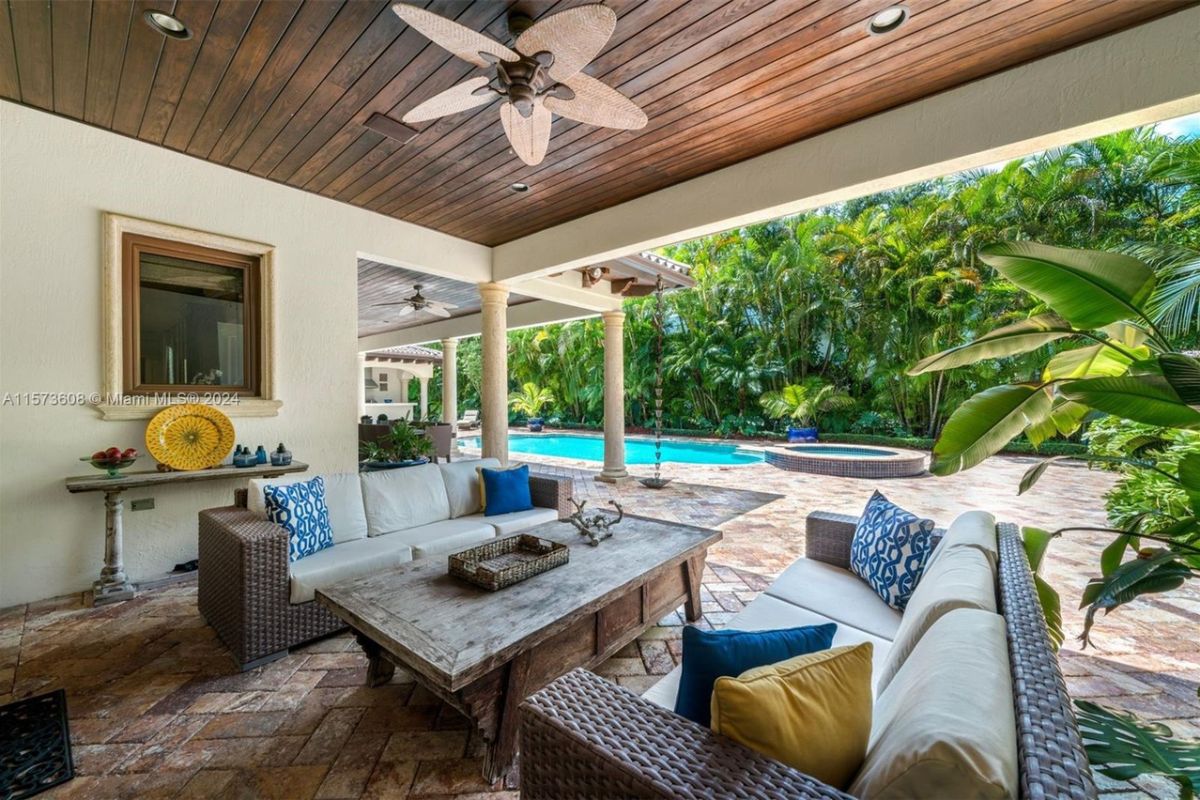 A patio with a ceiling fan, couches, and a center table.