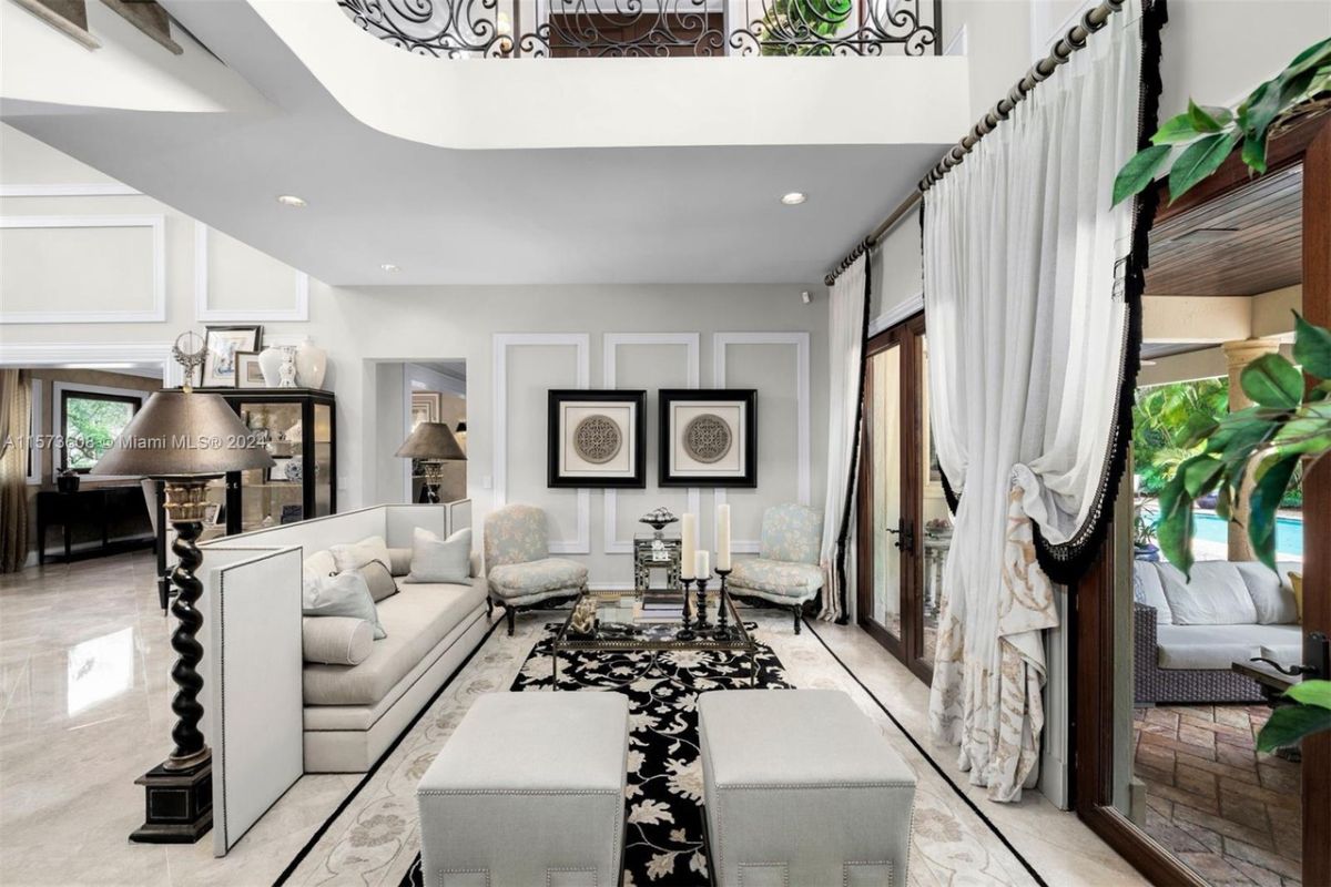 A living room with a white couch, chairs, and a glass center table.