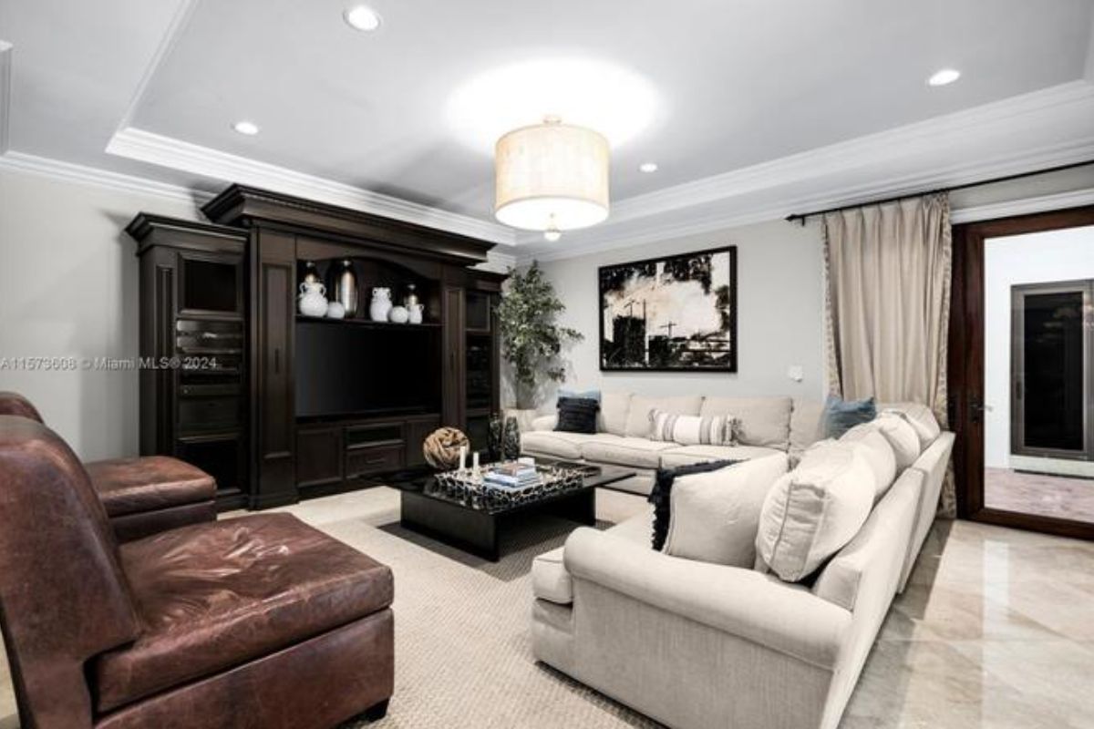 A living room with a cabinet, TV, painting, couches, and a center table.