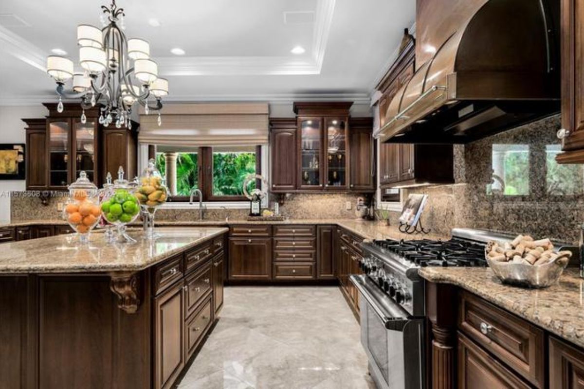 A kitchen with an island, countertops, a chandelier, cabinets, and kitchen appliances.