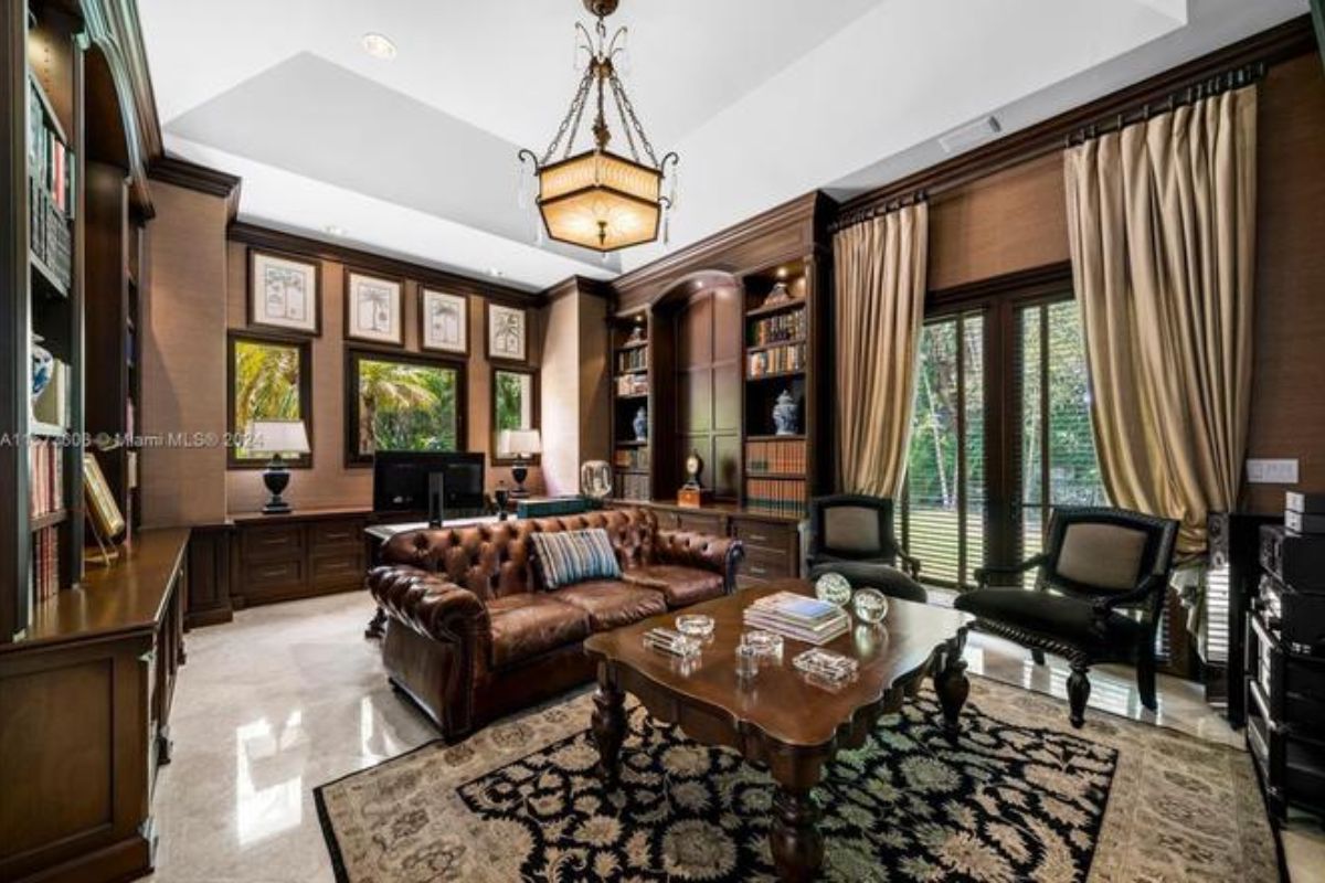 A home office with cabinets, shelves, a couch, chairs, a center table, and a desk.