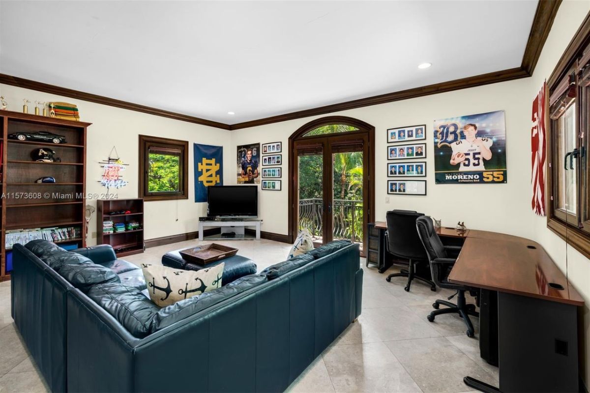 A home office with shelves, a couch, chairs, a center table, a TV, and a desk.