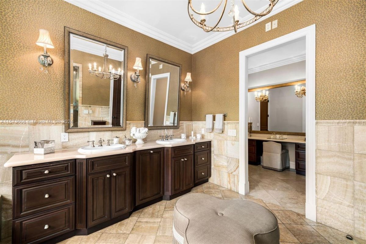 A bathroom with dual vanities, mirrors, and cabinets.