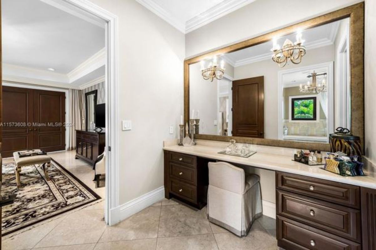 A powder room with a countertop, mirror, chair, and drawers.