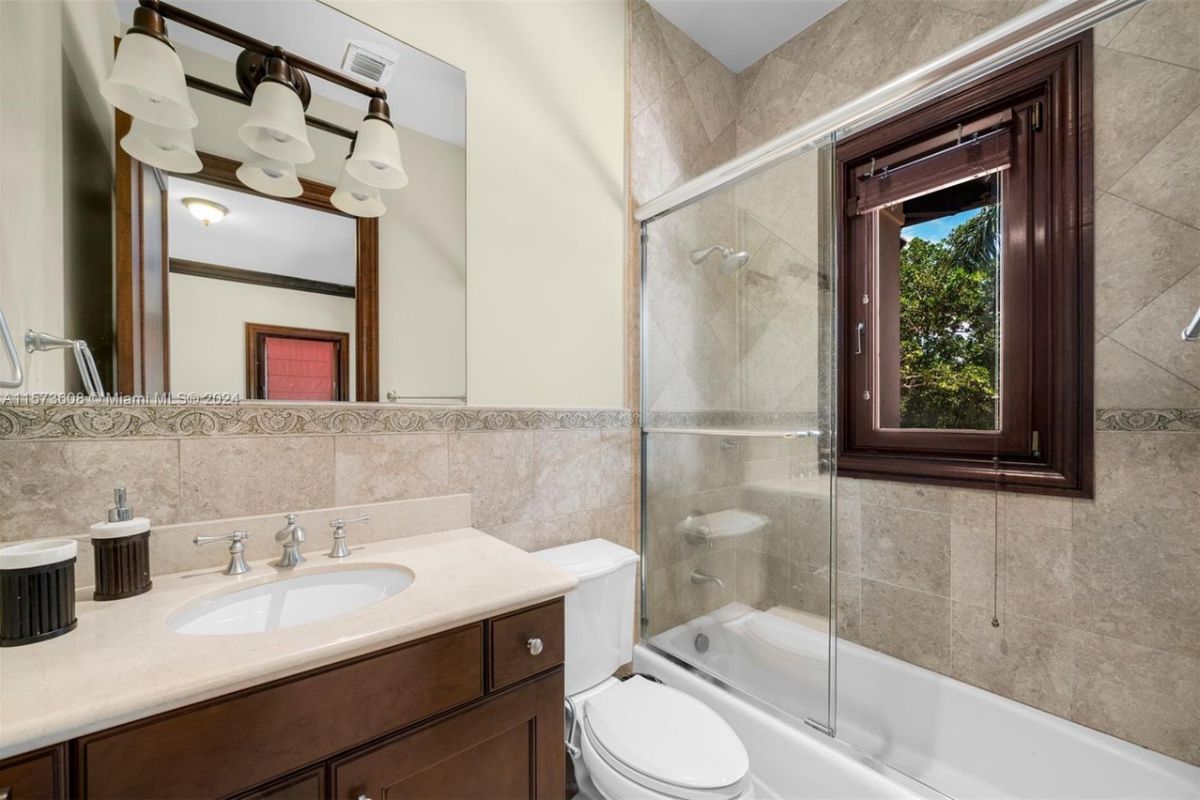 A bathroom with vanity, mirror, cabinet, toilet, and bathtub.