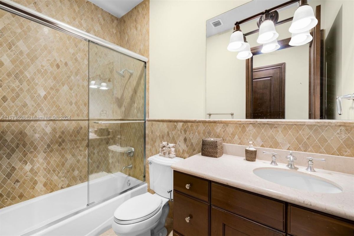 A bathroom with vanity, mirror, cabinet, toilet, and bathtub.