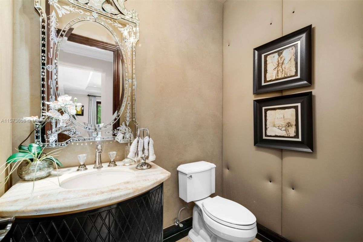 A bathroom with a vanity, mirror, and toilet.