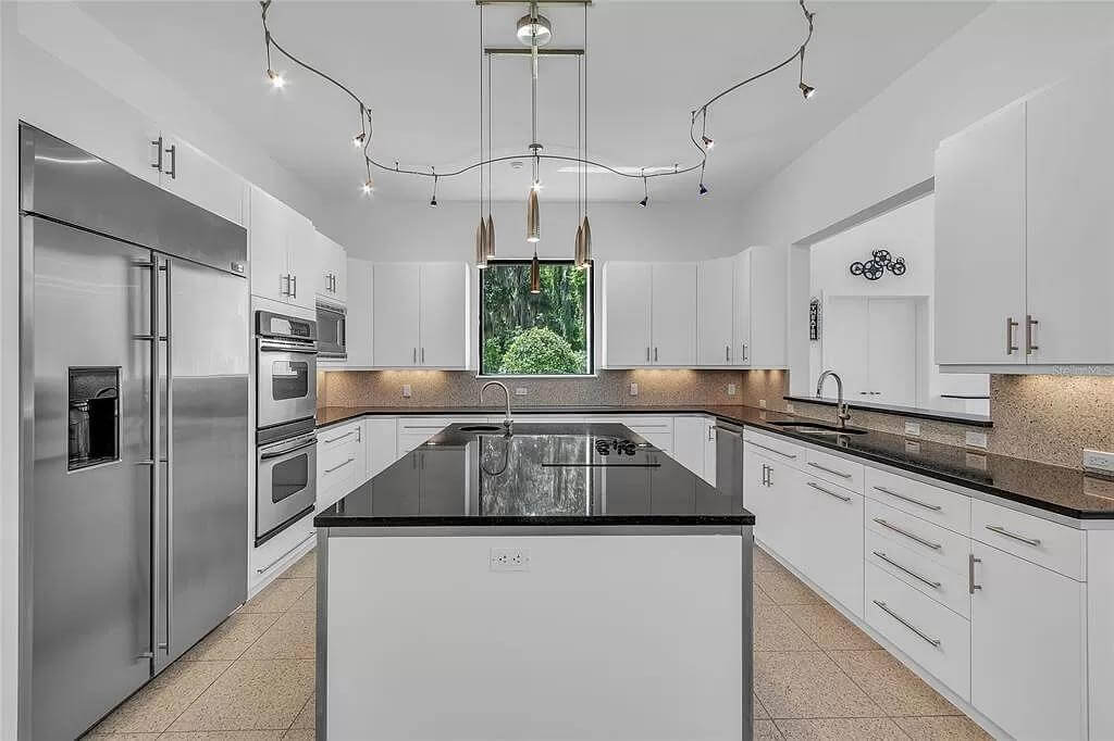 Kitchen with white cabinetry and a center island with a prep sink.