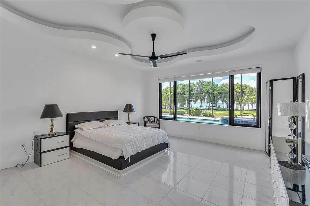 Primary bedroom with a decorative tray ceiling and a black bed over the tiled flooring.