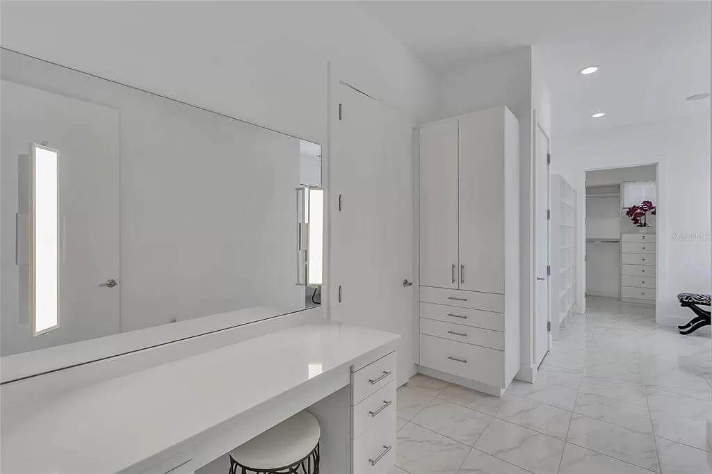 Primary walk-in closet with a built-in vanity and full-height cabinets.