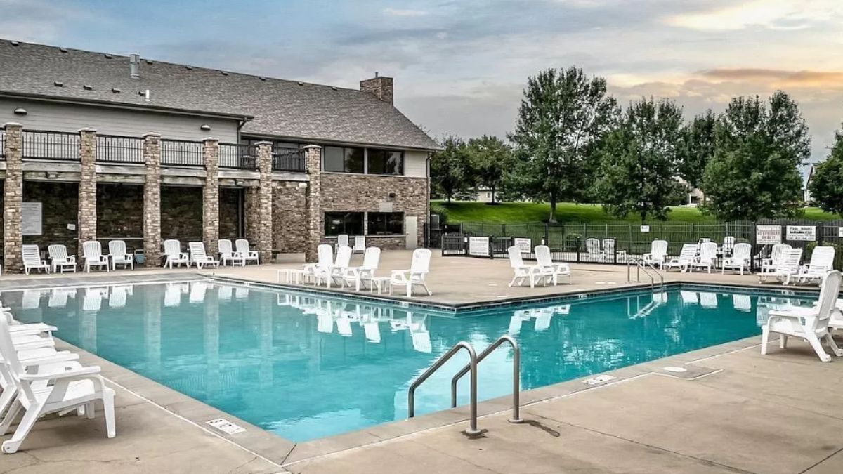 A swimming pool with lots of chairs on the poolside.