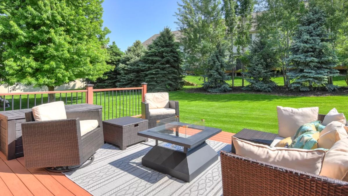 A deck with a rug, chairs, and a center table.