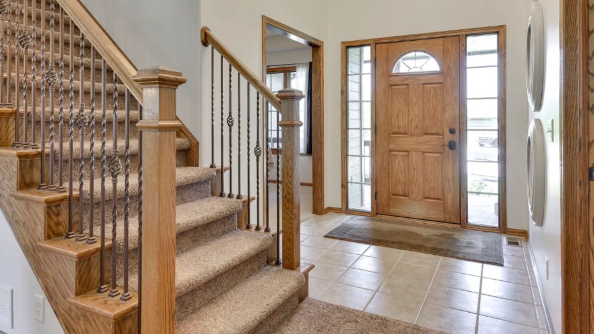 A foyer with tiled floor, a rug, and a staircase.