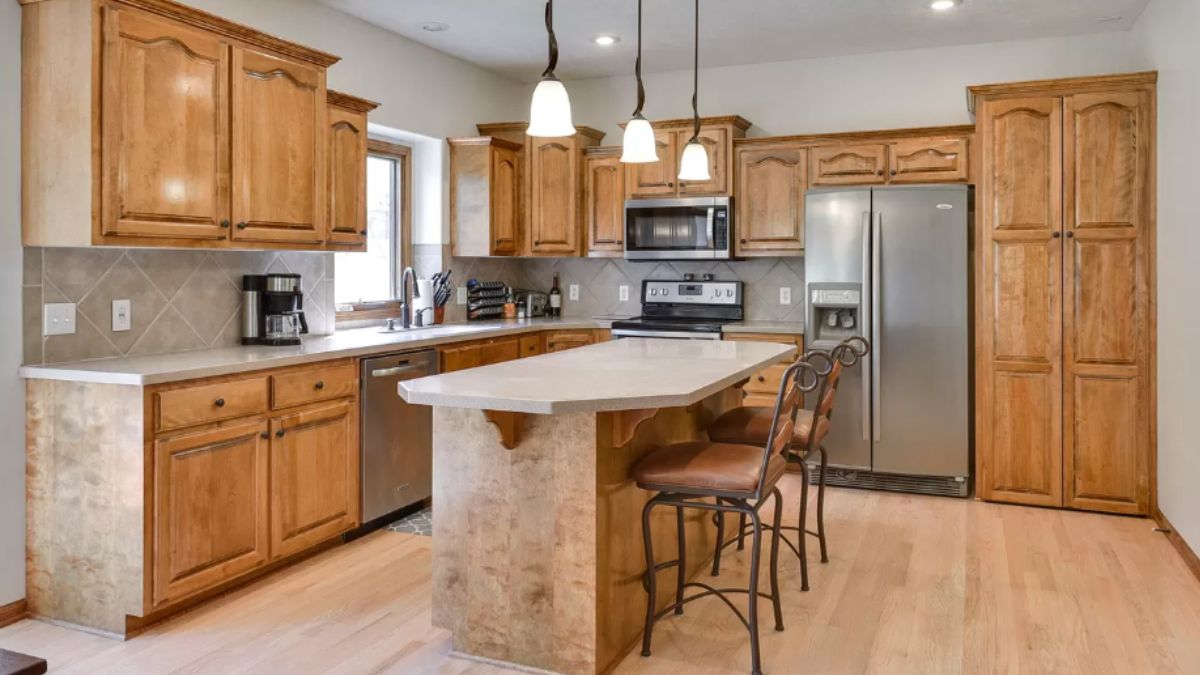 A kitchen with countertops, chairs, a sink, cabinets, and kitchen appliances.