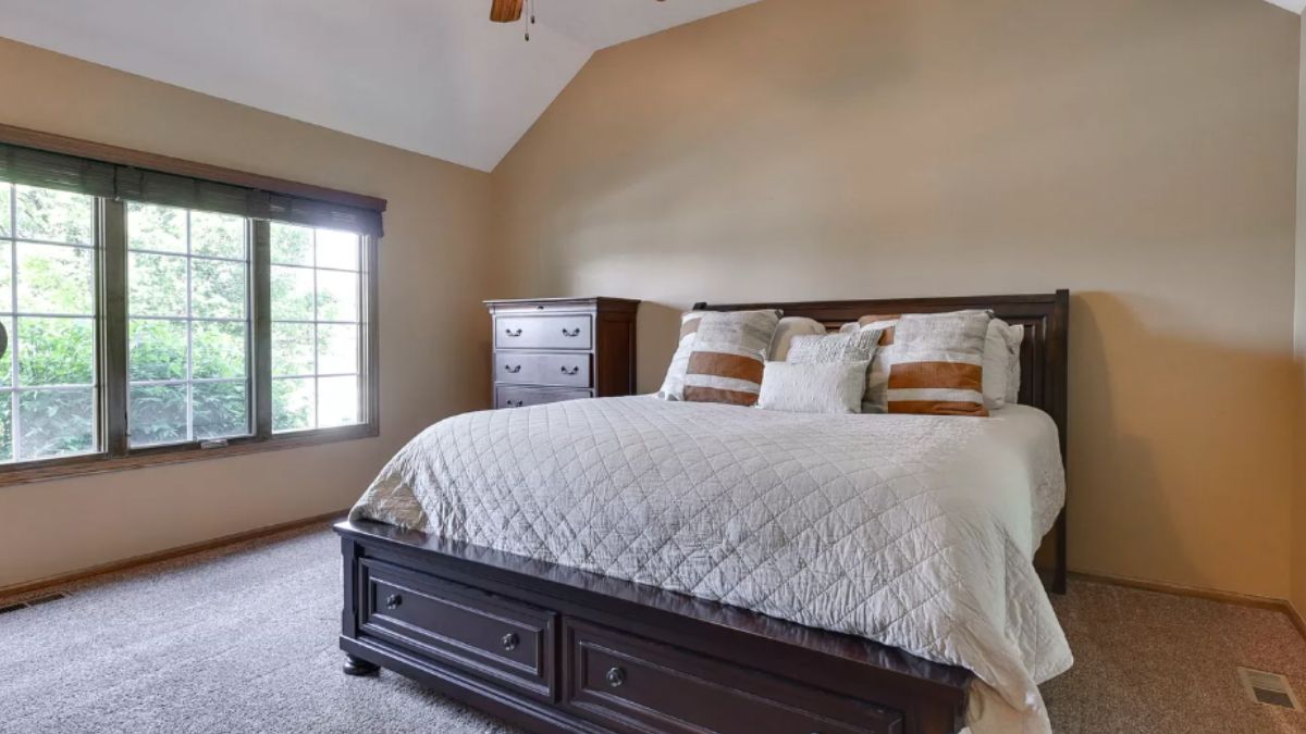 A bedroom with a bed, a cabinet, and a window.