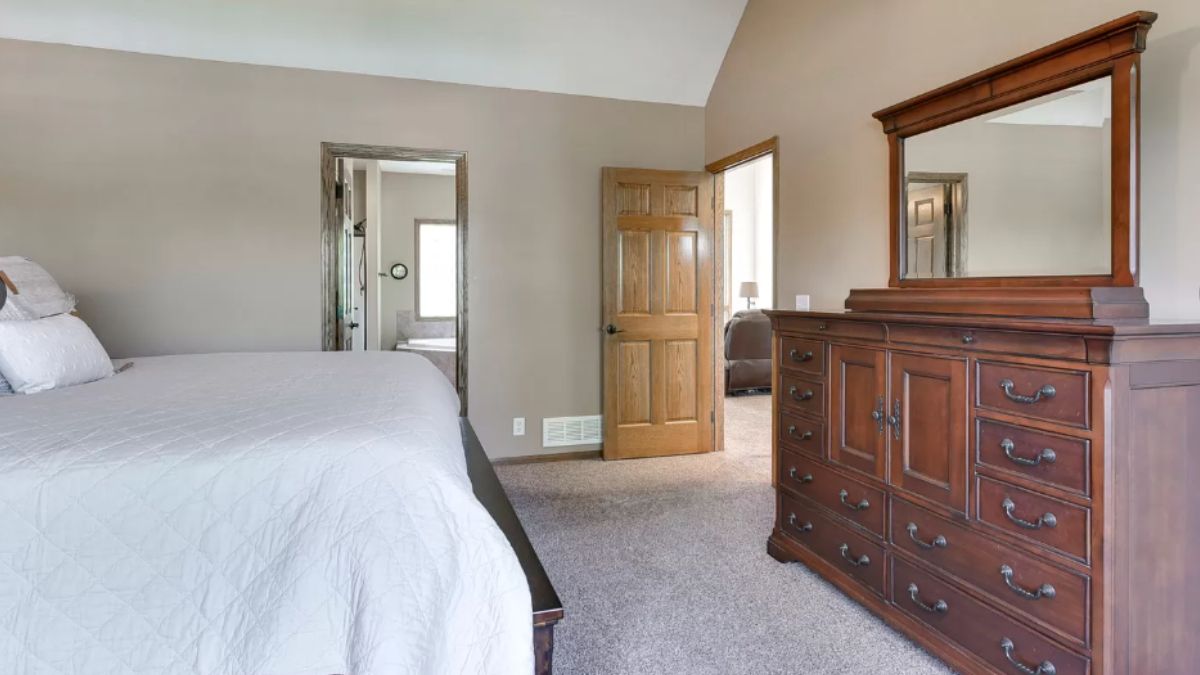 A bedroom with a bed, a mirror, and cabinets.