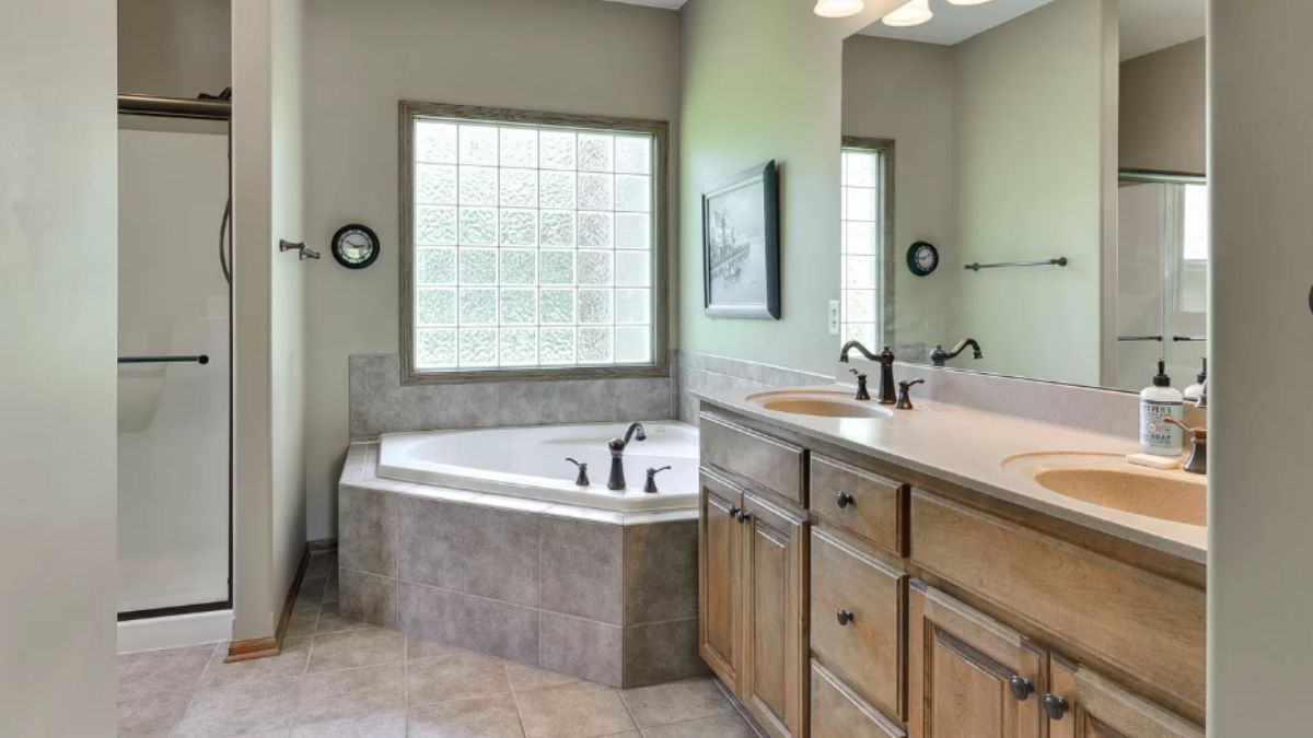 A bathroom with a vanity, mirror, cabinets, and bathtub.