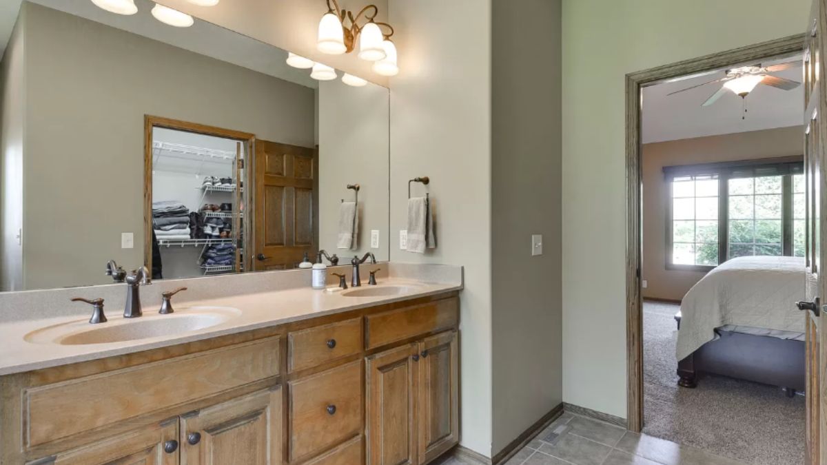 A bathroom with dual vanities, a mirror, and cabinets.