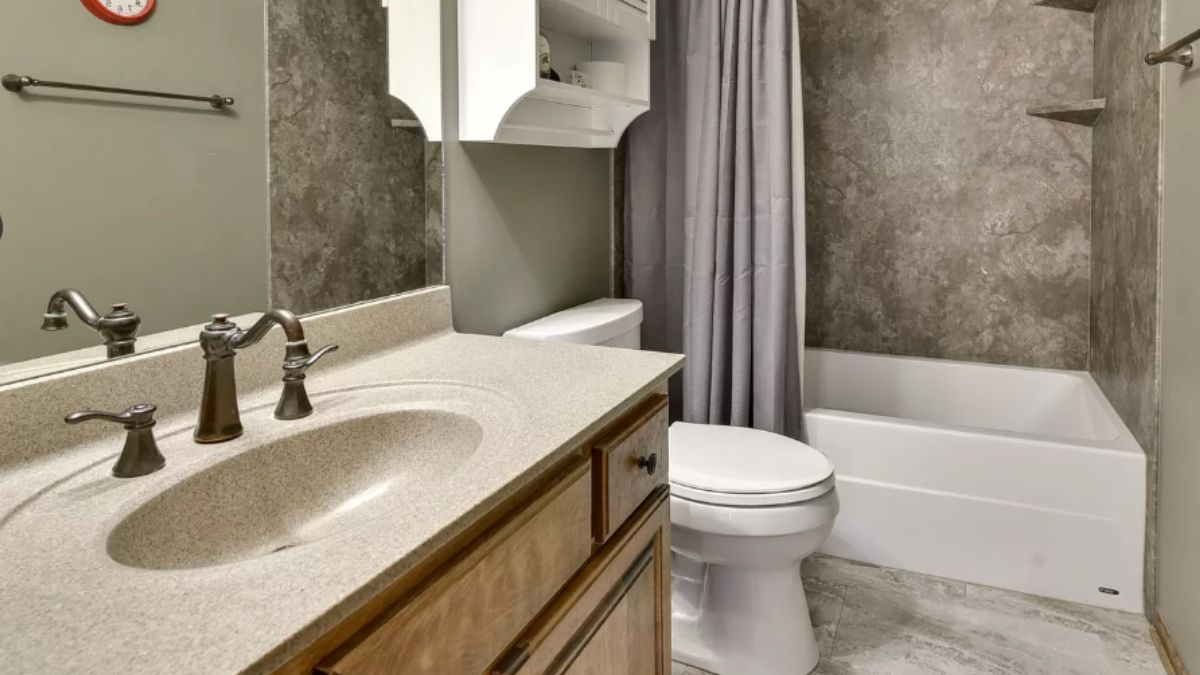 A bathroom with a vanity, cabinet, toilet, and bathtub.