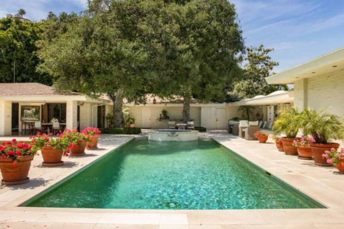 A swimming pool with a jacuzzi and potted plants on the poolside.