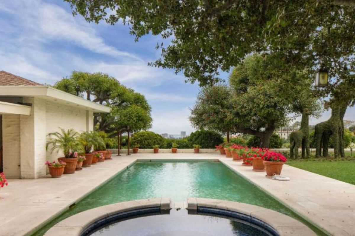 A swimming pool with a jacuzzi and potted plants on the poolside.