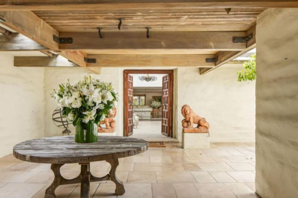 A porch with an exposed beam ceiling and a round table with a vase.