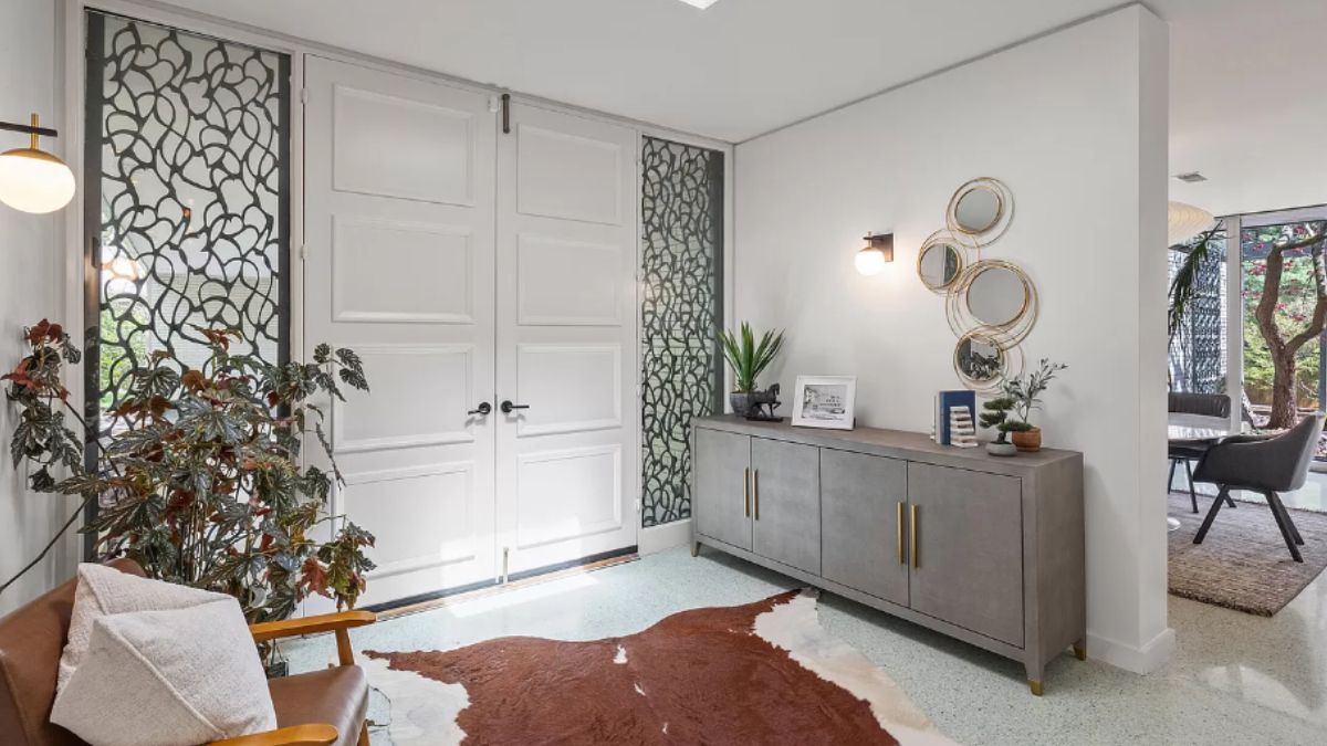 A foyer with a cabinet, chair, and houseplant.