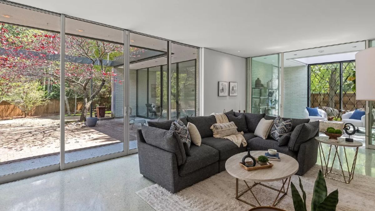 A living room with a rug, couch with pillows, and coffee tables.