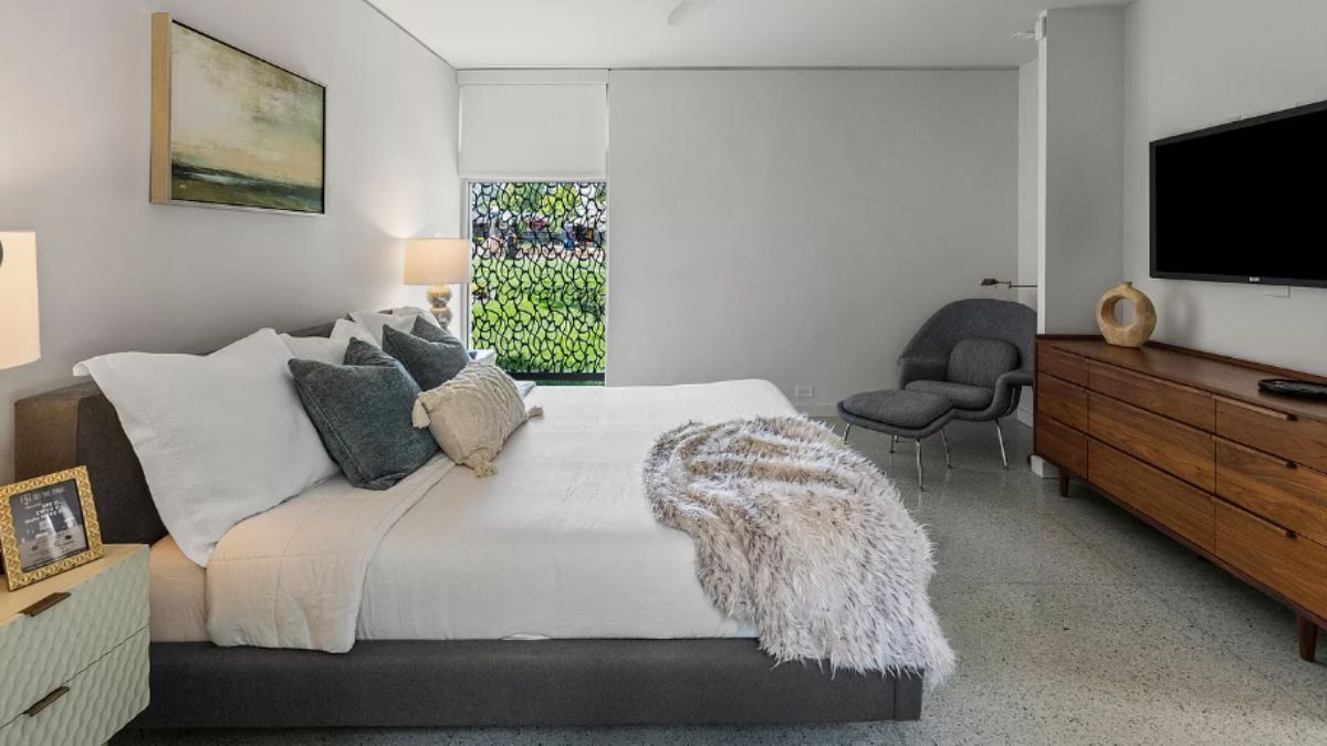 A bedroom with a bed, nightstands, chair, cabinet, and TV.