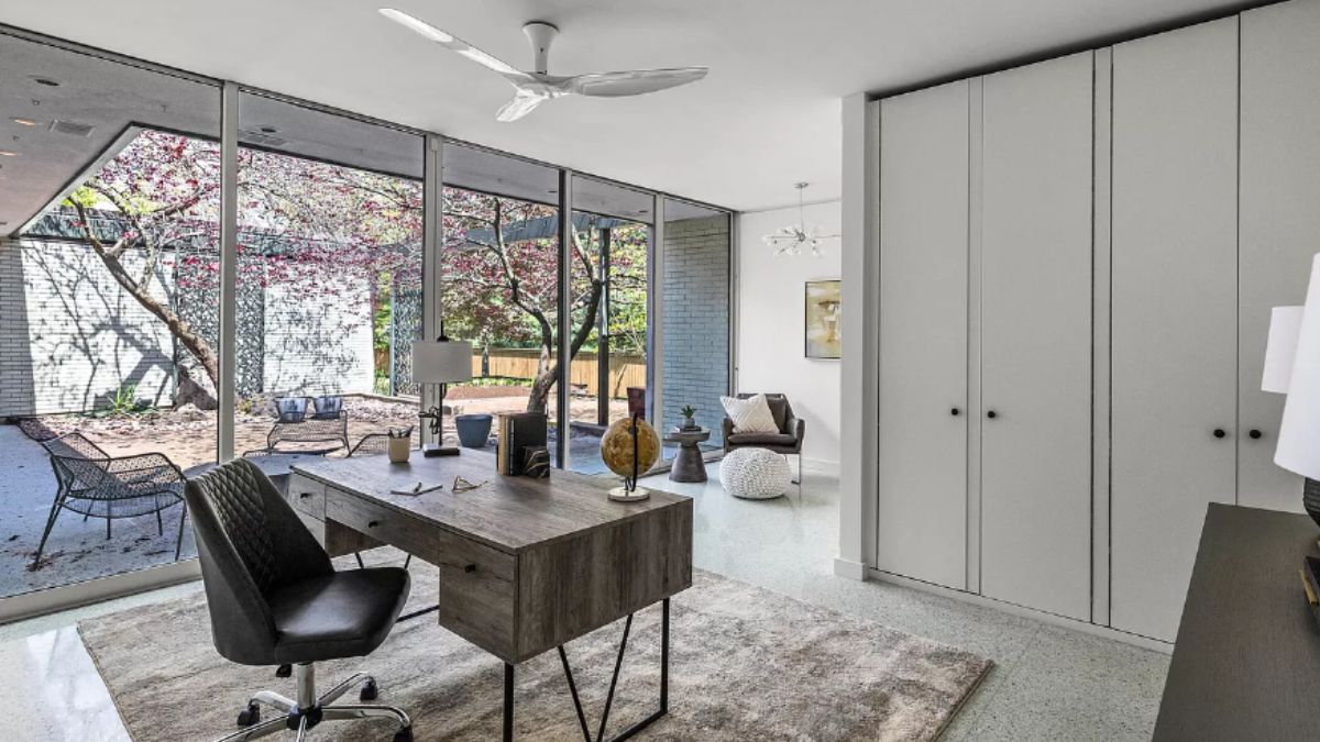 A home office with a rug, ceiling fan, desk, and chair.