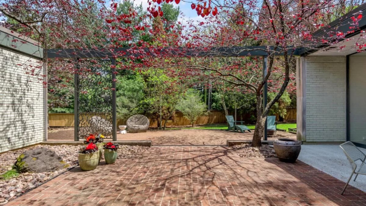 A courtyard with a brick floor, plants, and flowers.