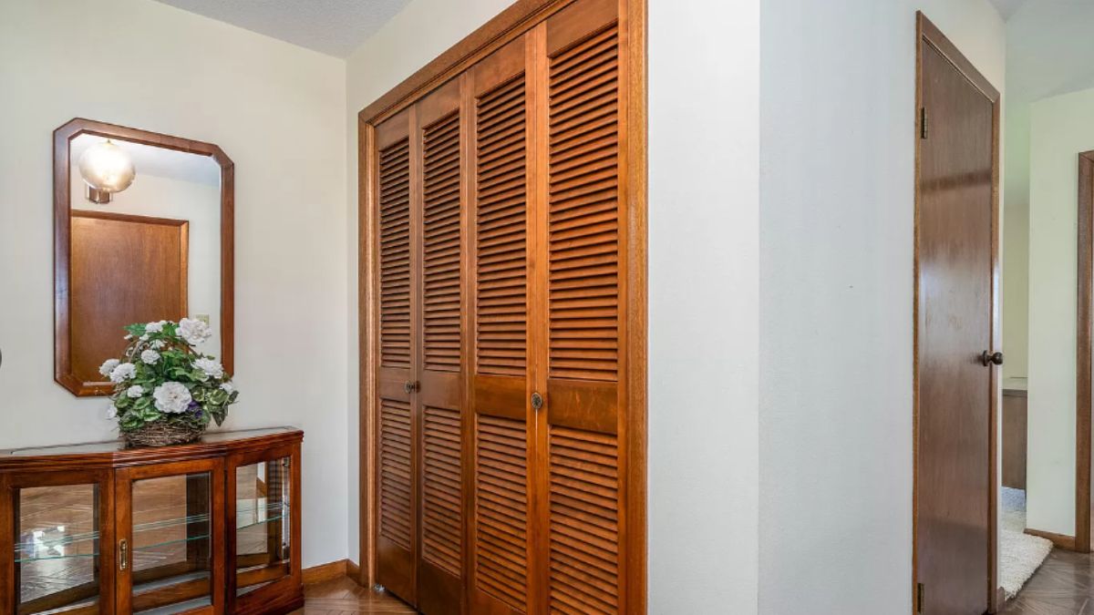 A foyer with a mirror and a cabinet with a vase on top.