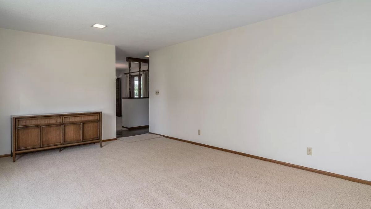 A living room with a cabinet, white walls, and a white ceiling.