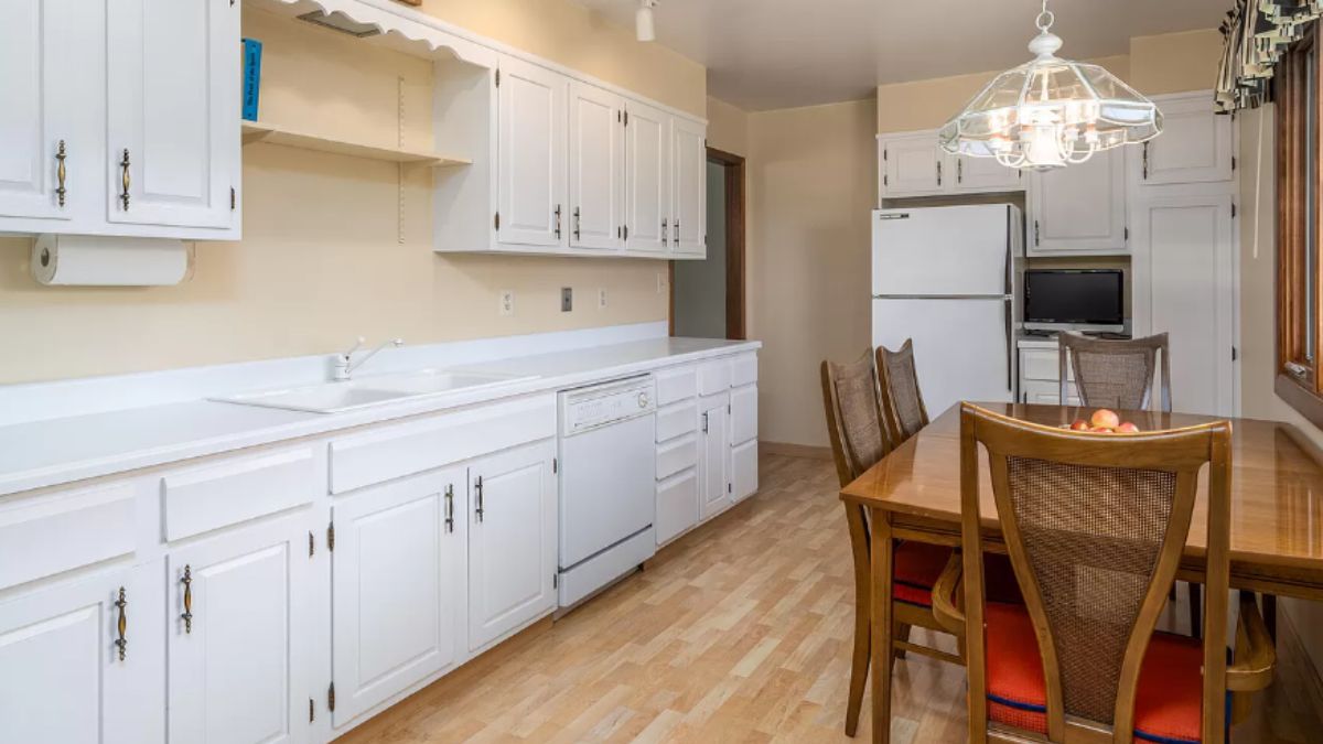 A kitchen with a countertop, sink, cabinets, and a dining table with chairs.