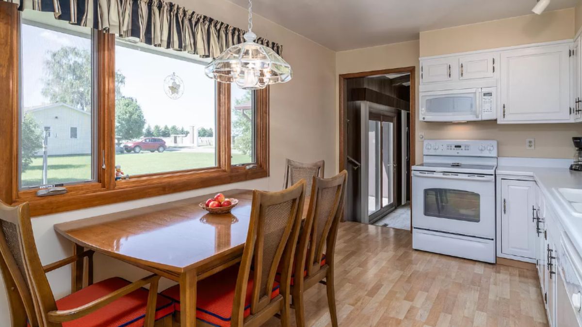 A kitchen with a countertop, sink, cabinets, and a dining table with chairs.