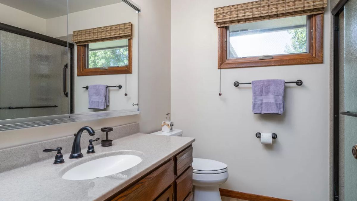 A bathroom with a vanity, mirror, and toilet.