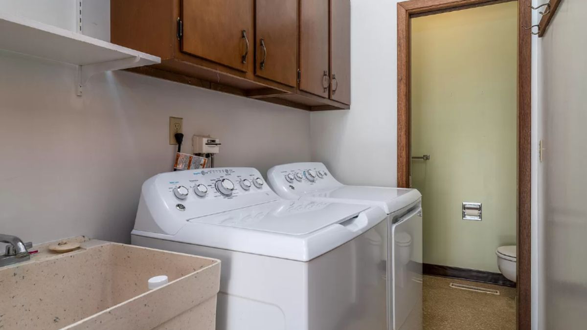 A laundry room with a sink, cabinets, and washing machines.