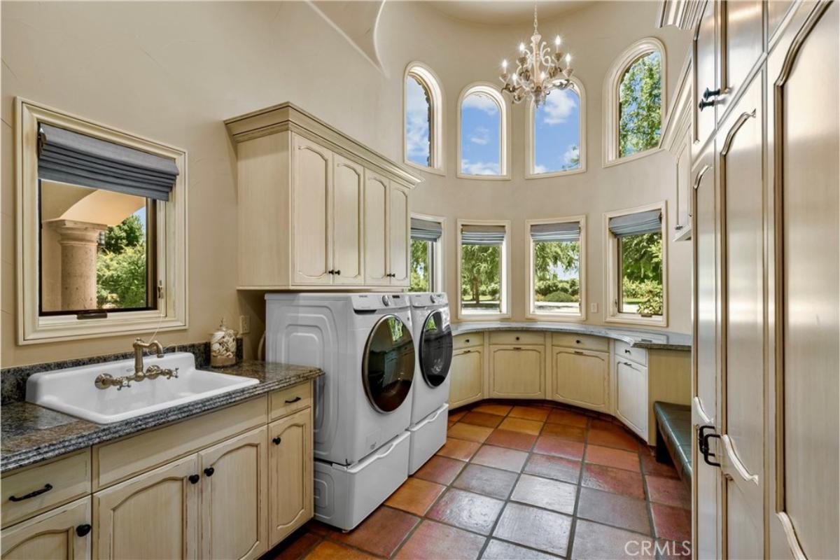 Laundry room with a chandelier and custom cabinetry,