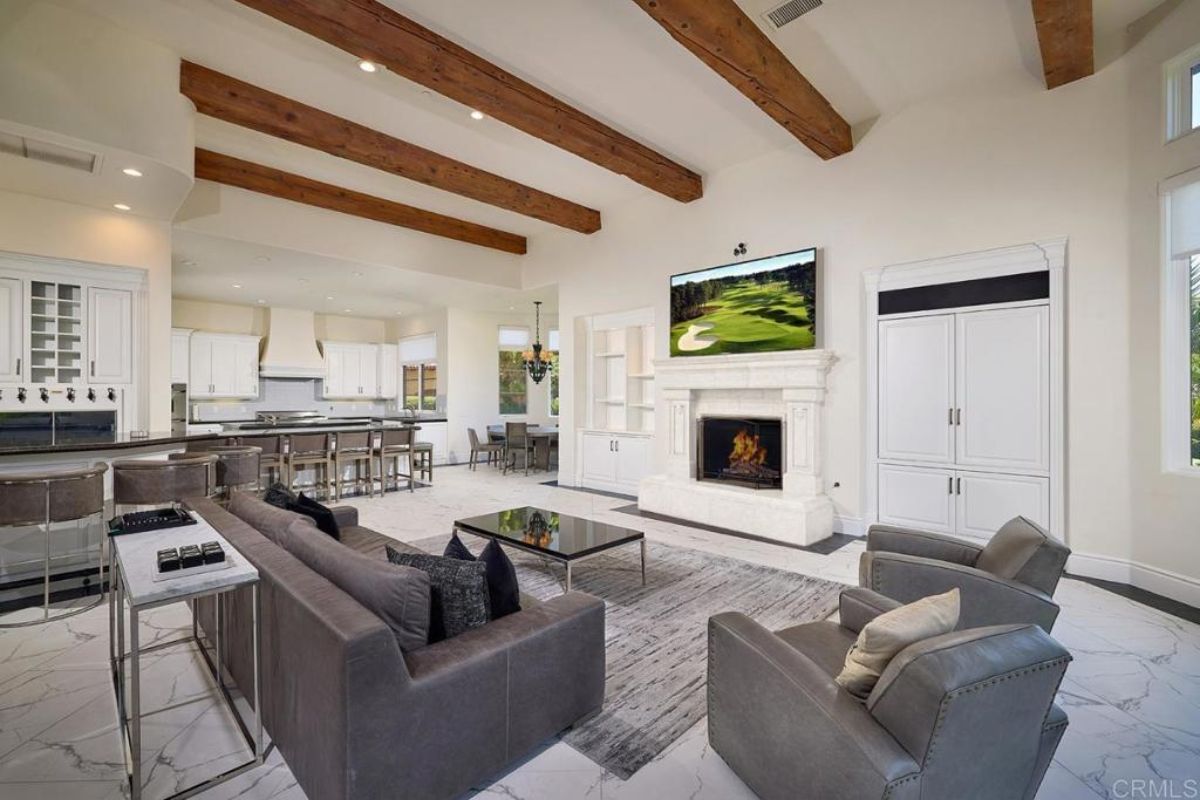 A great room with exposed beam ceiling, living space, dining area, and kitchen.