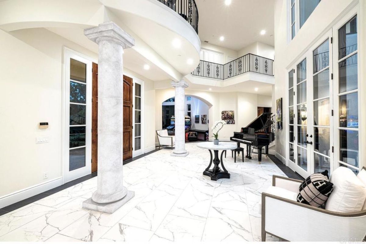 A foyer with tiled floor, center table, piano, and chairs.