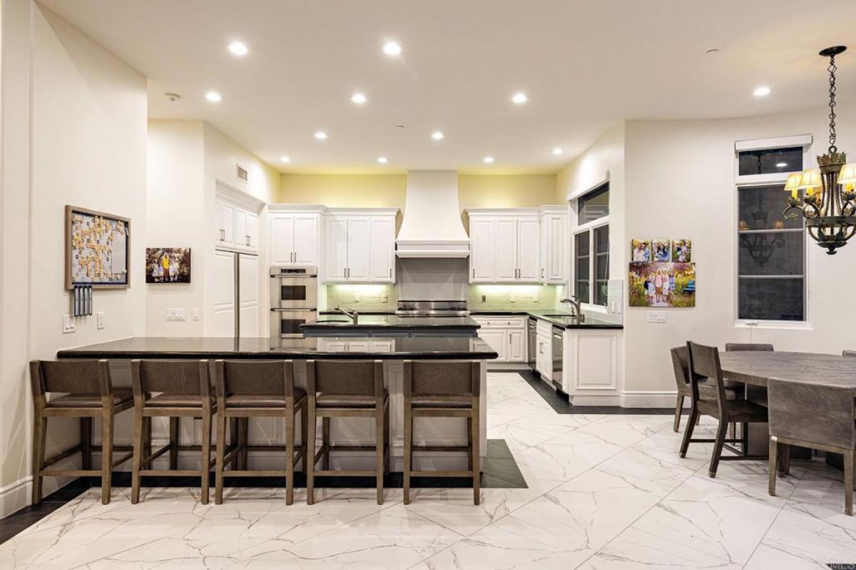 A kitchen with countertops, chairs, sink, and cabinets.