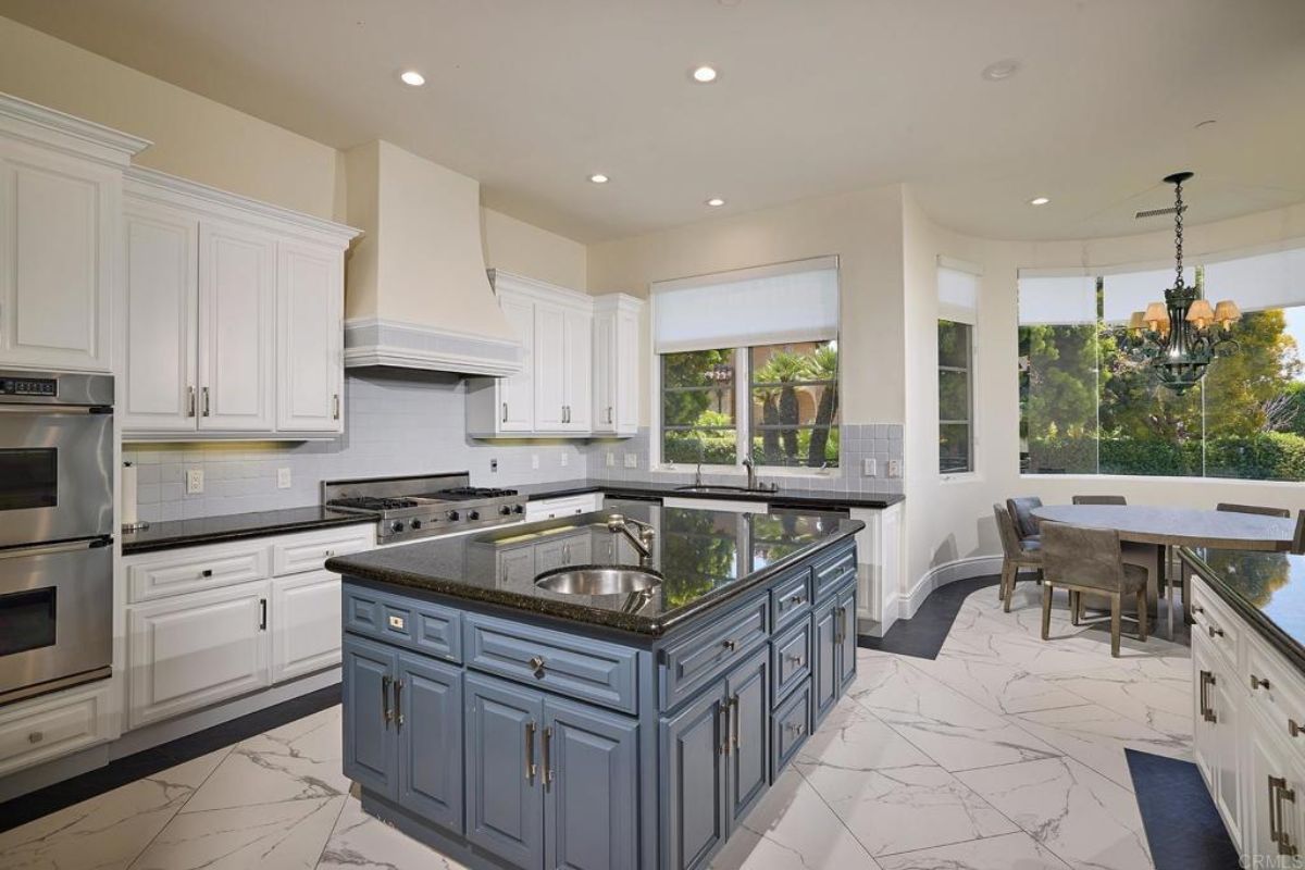 A kitchen with a center island, sink, countertops, cabinets, and kitchen appliances.