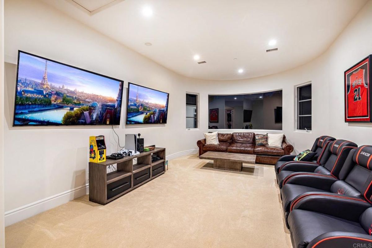 A home theater with chairs, a couch, a coffee table, and two TVs.