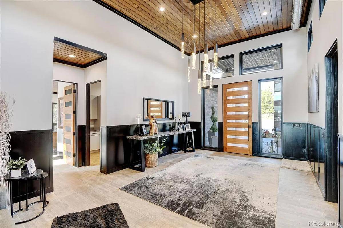 Foyer with a glazed front door and an iron console table under the wood-paneled ceiling.