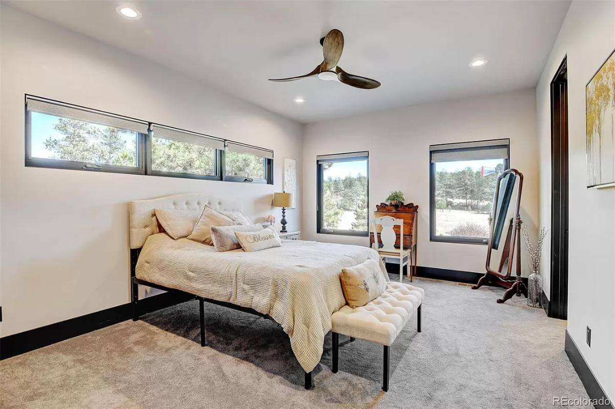 Bedroom with a full-length mirror and a tufted bed complemented with a matching bench.