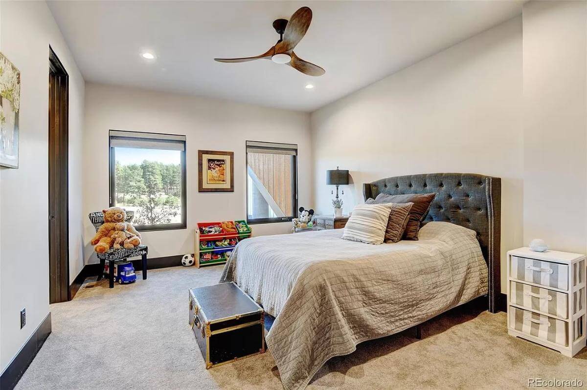 Bedroom with a wingback bed, a patterned chair, and a rustic storage chest over the carpeted floor.